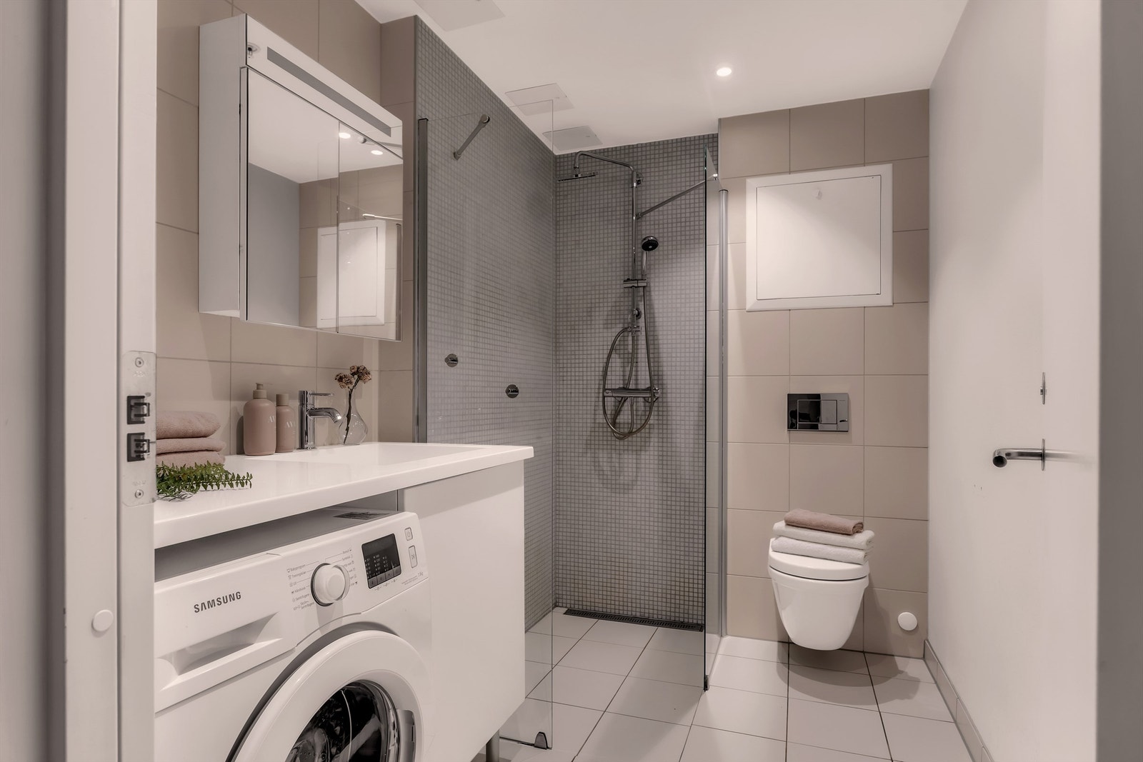 Delikat, flislagt baderom fra byggeår med gulvvarme. Opplegg for vaskemaskin under servantinnredningen. Galleribilde