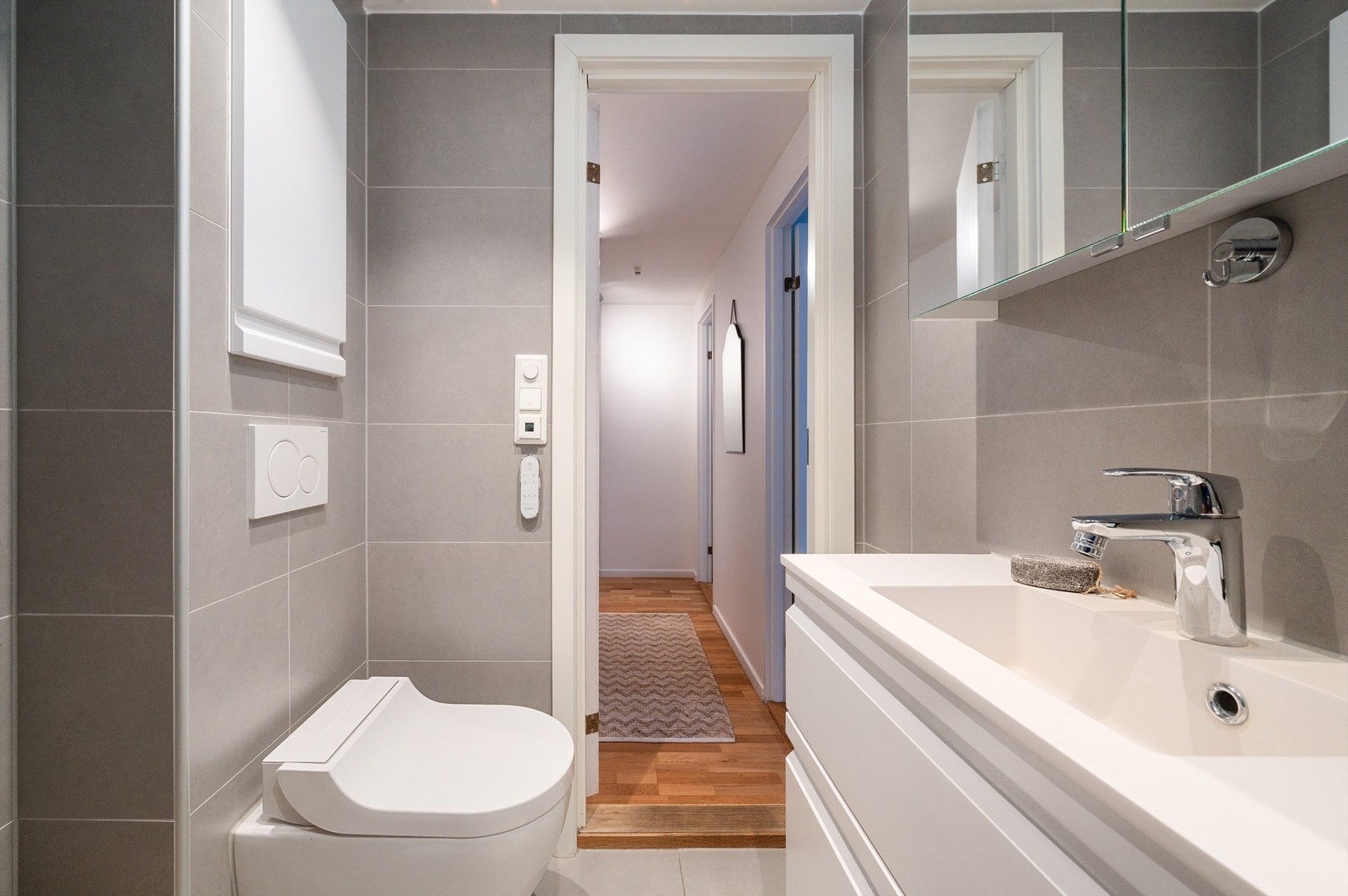 Rommet har flislagte overflater, vegghengt toalett og dusj med innfellbare glassdører. Galleribilde