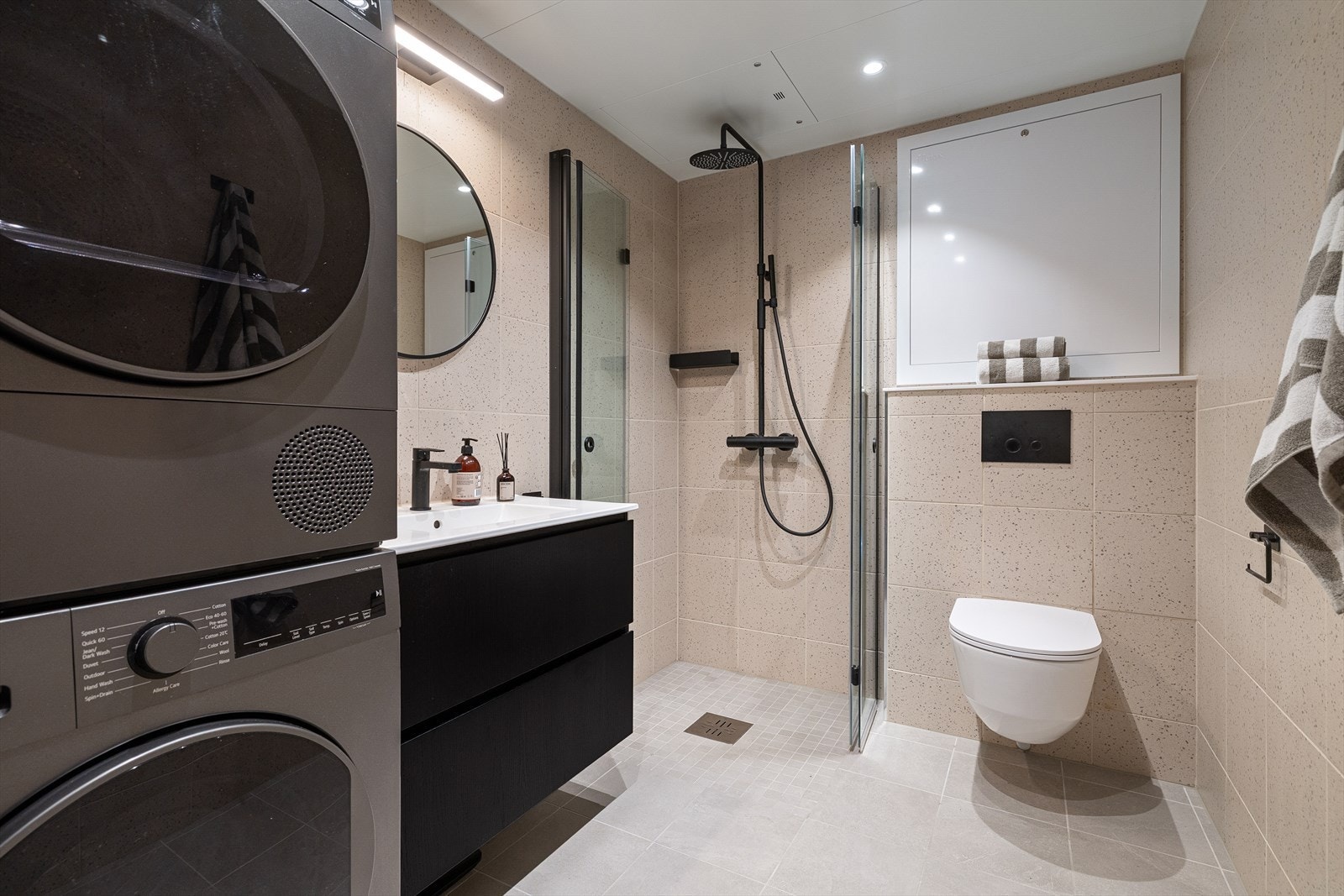 Hovedbadet er av god størrelse med lyse fliser på gulv og vegger samt vannbåren varme i gulvet. Sorte detaljer på innredning og ny speilbelysning. Her er det også gjort tilvalg på trykknapp og regnfalldusj. Galleribilde