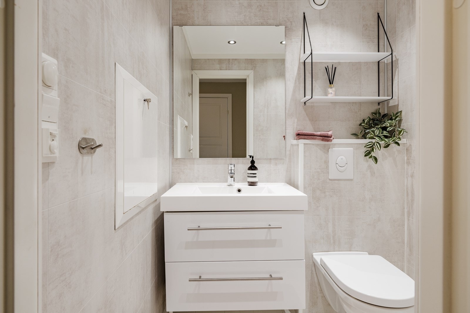 Flislagt toalettrom med våtromsplater på vegger og malt tak med innfelte downlights Galleribilde