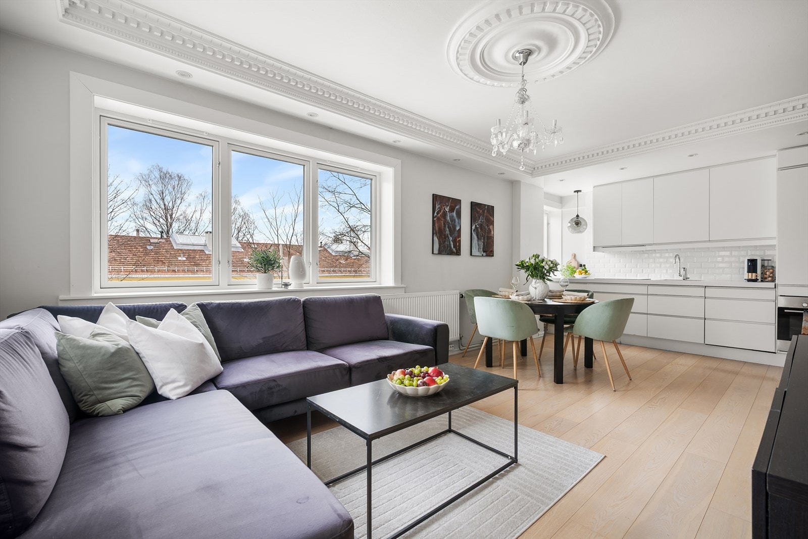 Lys og luftig stue med åpen løsning mot kjøkken, noe som skaper en sosial og moderne allromsfølelse Galleribilde