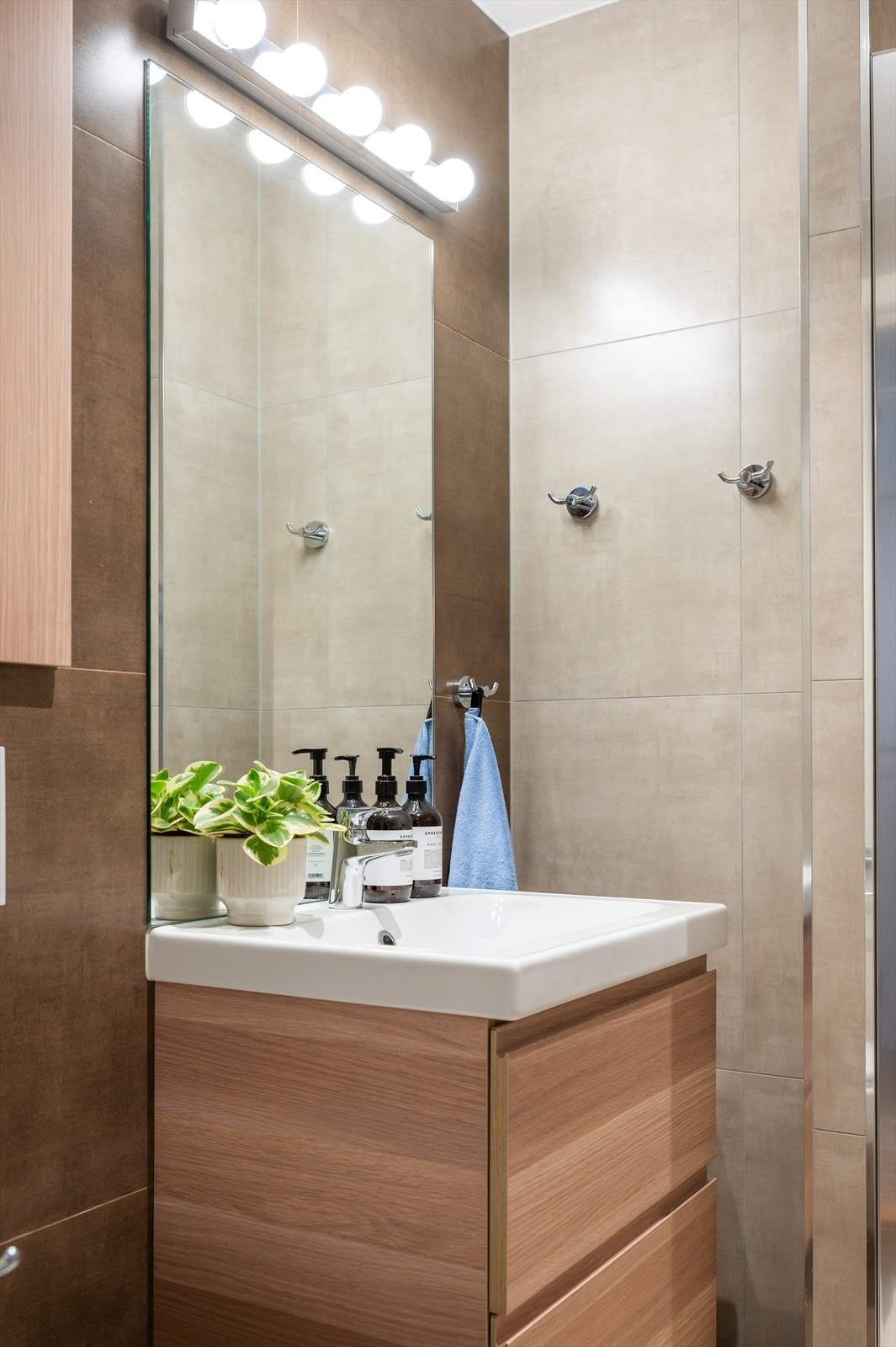 Badet er innredet med servantinnredning, vegghengt toalett og dusj med glassdør. Galleribilde