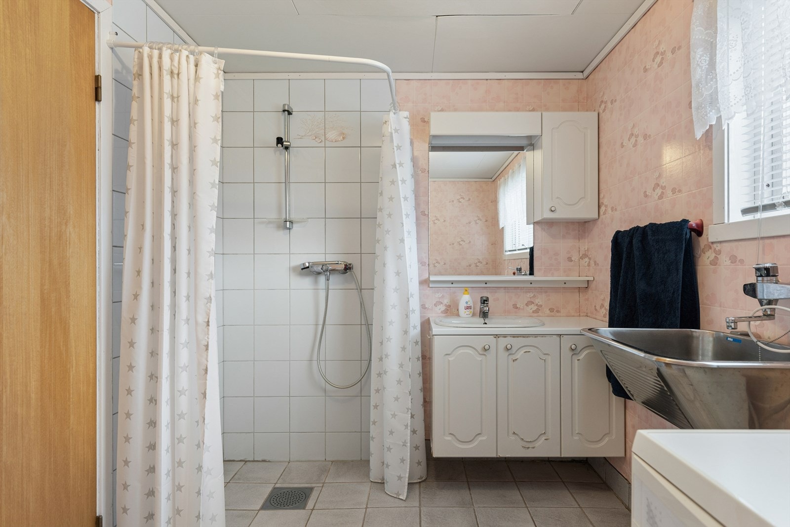 Bad/vaskerom med servant med møbel, dusj, utslagsvask, vaskemaskin og toalett. Galleribilde