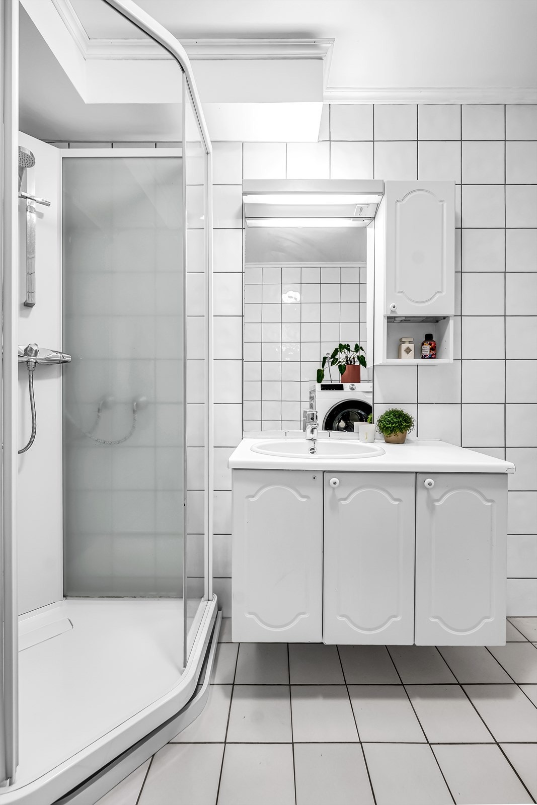 Dusjkabinett i hjørne med skyvedører i glass og veggmontert hånddusj. Galleribilde