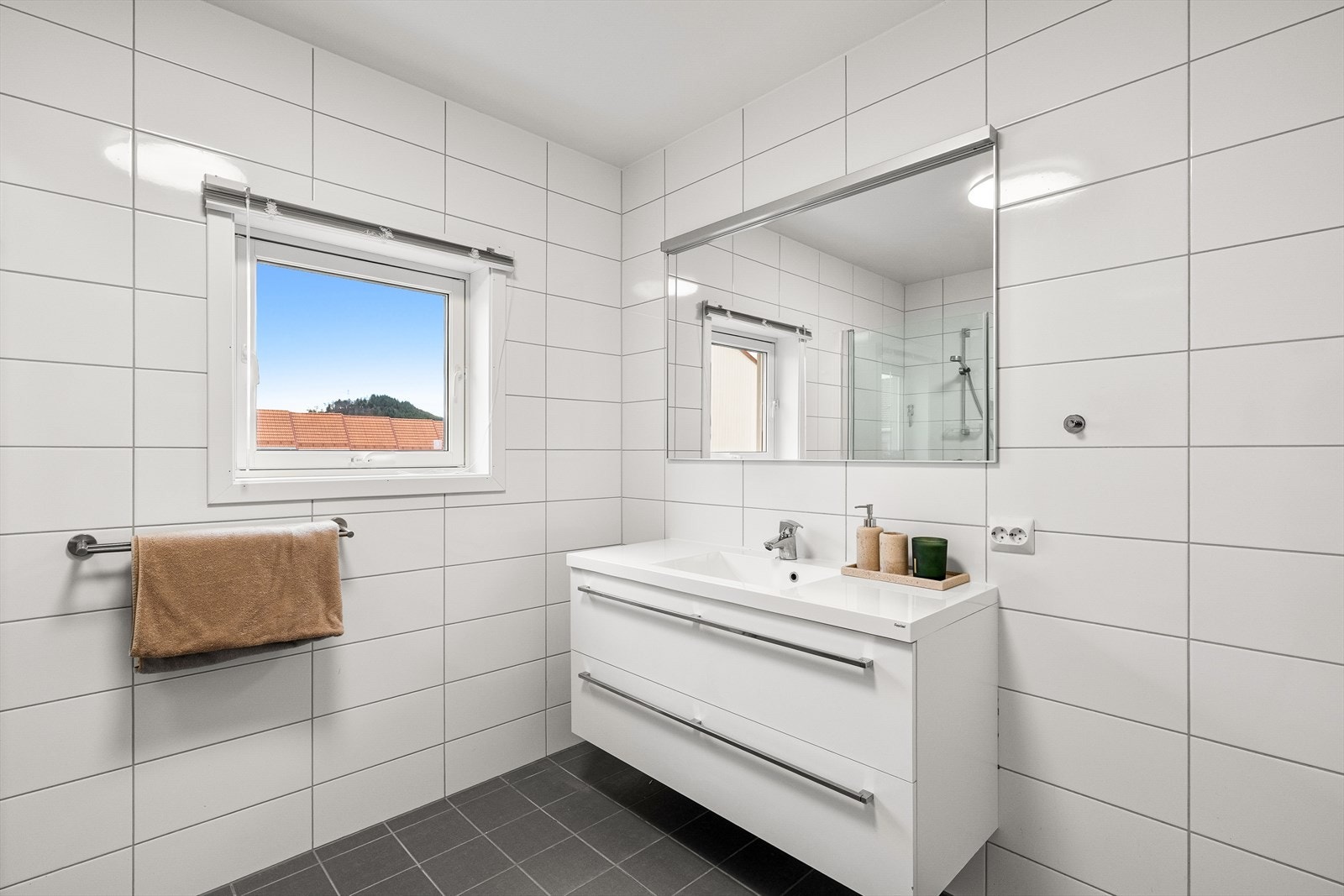 Badet er flislagt med vegghengt servant og dusjsone. Galleribilde