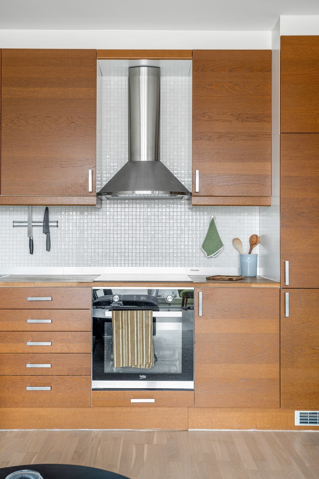 Her får du benkeplate i tre, mosaikkfliser på vegg over benk, rikelig med oppbevaring og sjenerøs arbeidsflate, perfekt for familiens kokk! Galleribilde