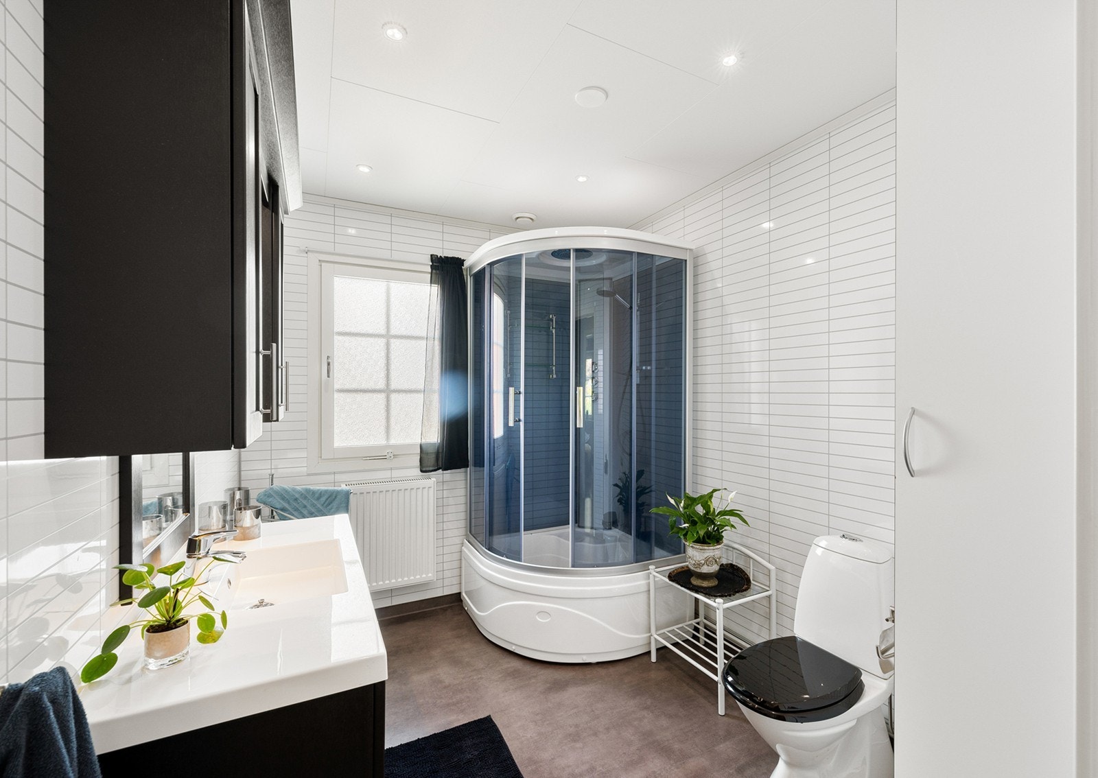 Moderne baderomsinnredning med god skapplass, servant, speil og lys med stikk og et dusjkabinett. Vindu som gir godt med naturlig lys, samt downlights i himling. Galleribilde