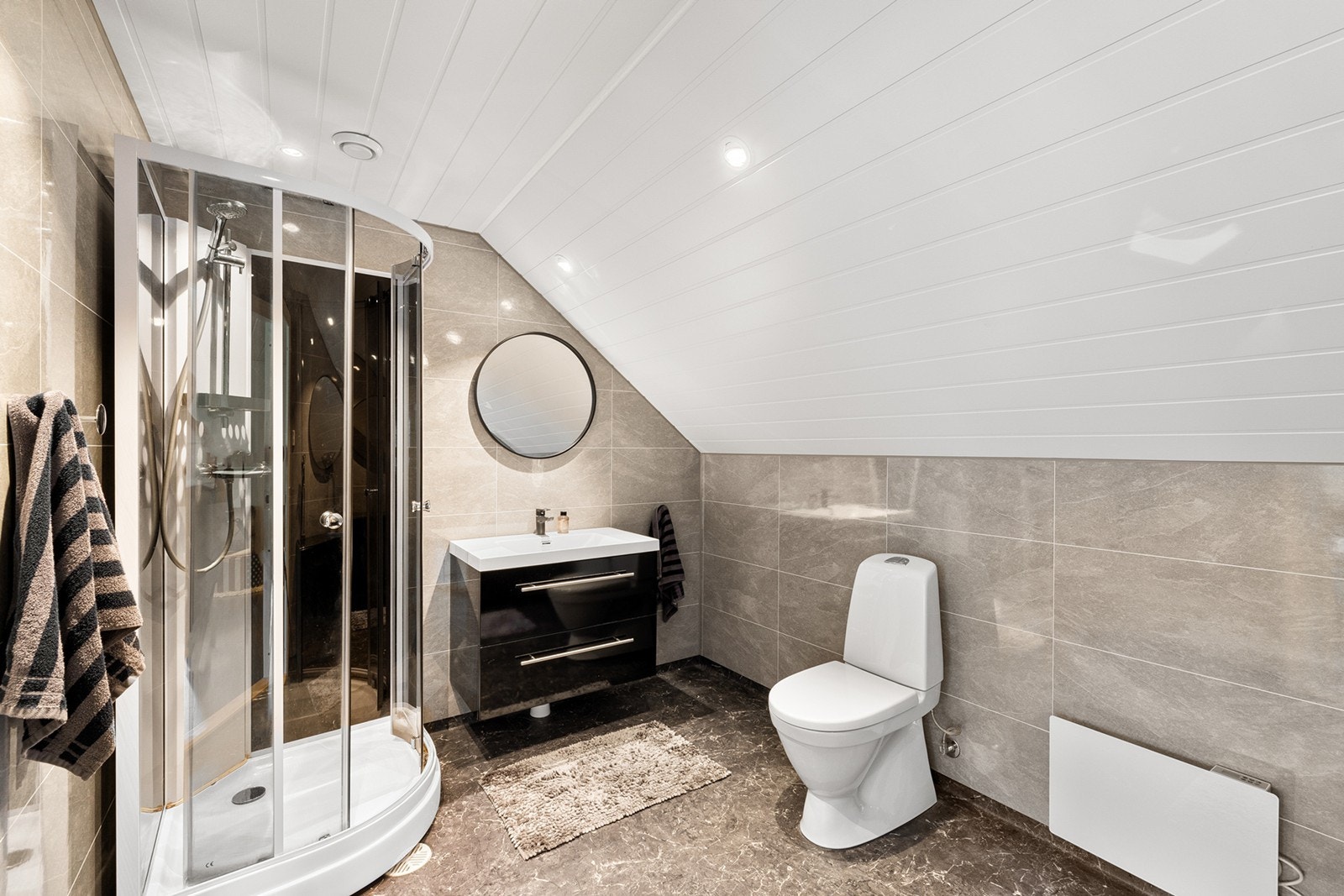 Flott bad med moderne baderomsplater, downlights i himling og pent gulvbelegg. Rommet er innredet med dusjkabinett, servant med møbel og speil, samt toalett. Galleribilde