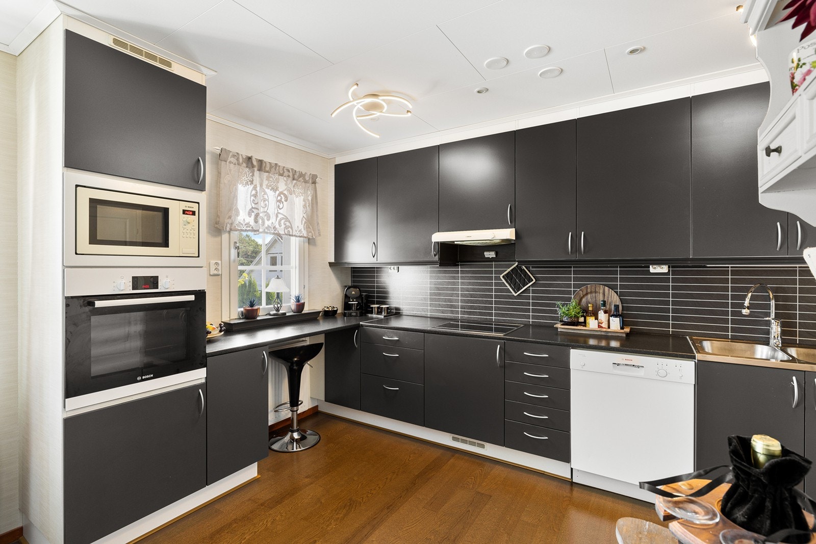 Moderne kjøkken med god skap- og benkeplass. Kjøkkenet er innredet med stilrene, mørke fronter og laminert benkeplate. Galleribilde