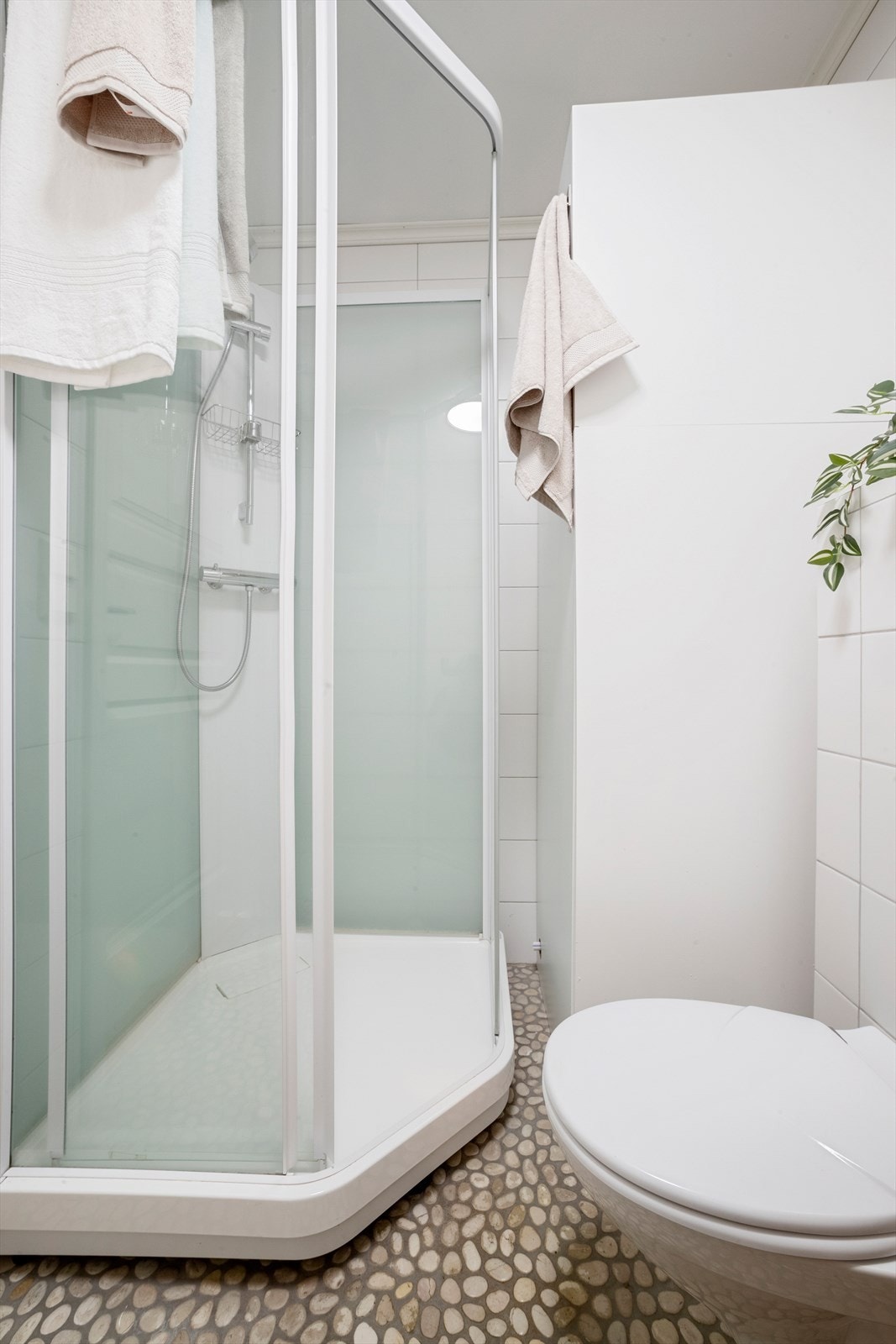 Rommet er utstyrt med et frittstående dusjkabinett, vegghengt toalett og servantinnredning. Galleribilde