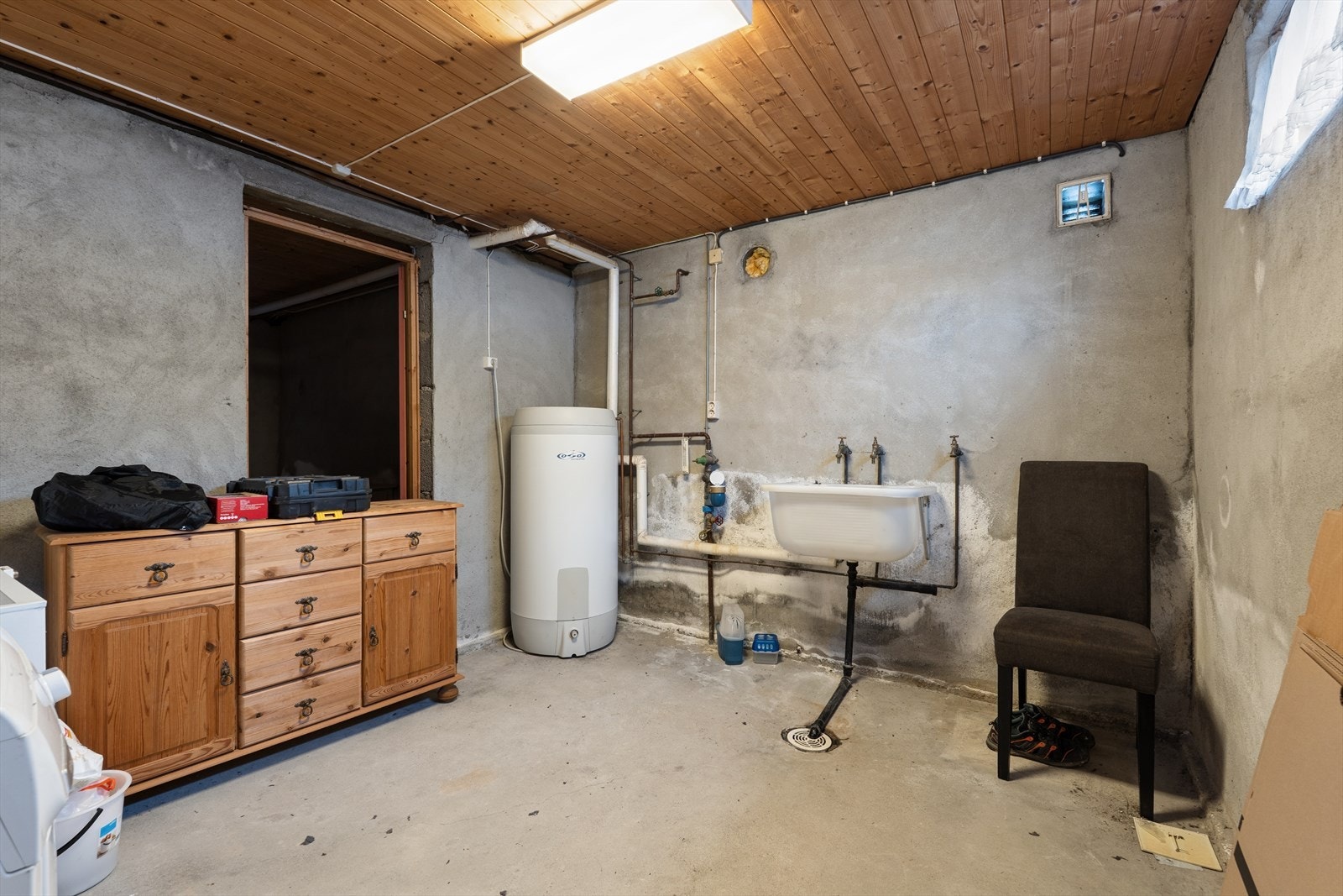 Vaskekjeller med opplegg for vaskemaskin og utslagsvask på vegg. Galleribilde