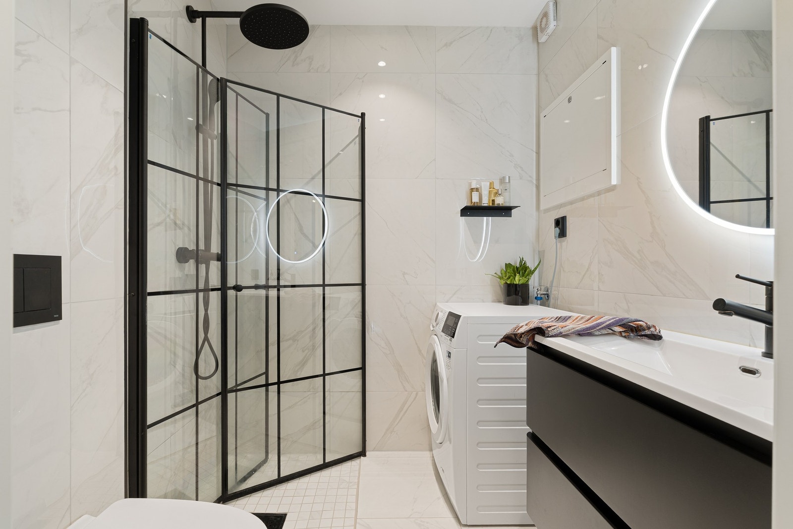 Svært lekkert flislagt baderom med moderne innredning og opplegg for vaskemaskin Galleribilde