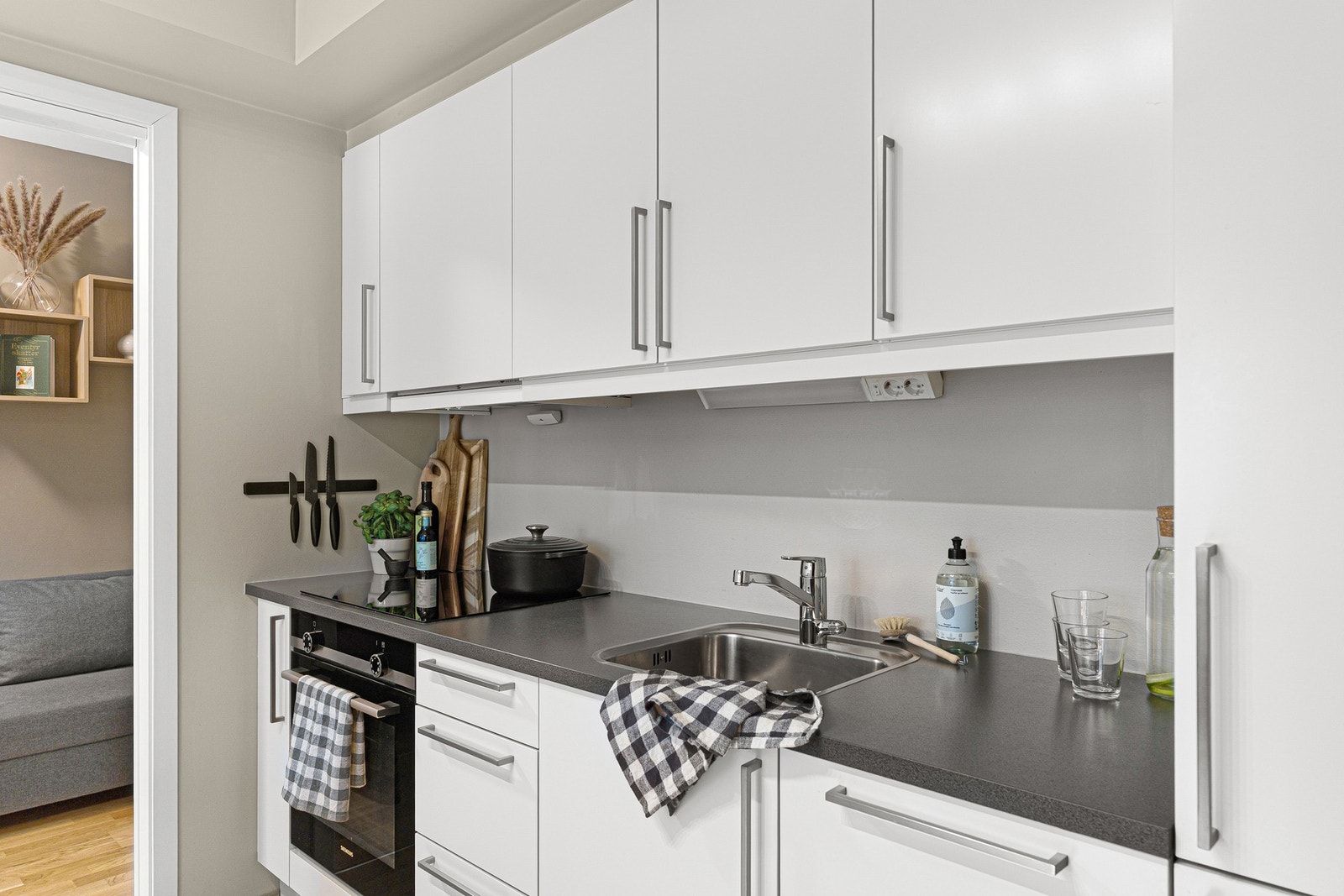 Stilrent kjøkken med integrerte hvitevarer som komfyr, kjøleskap, fryseskap og oppvaskmaskin. Galleribilde