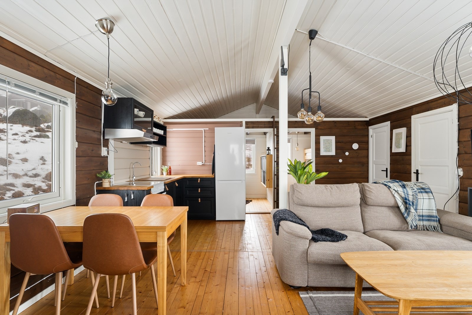 Koselig stue med åpen kjøkkenløsning. Beiset panel på veggene og tregulv. Galleribilde