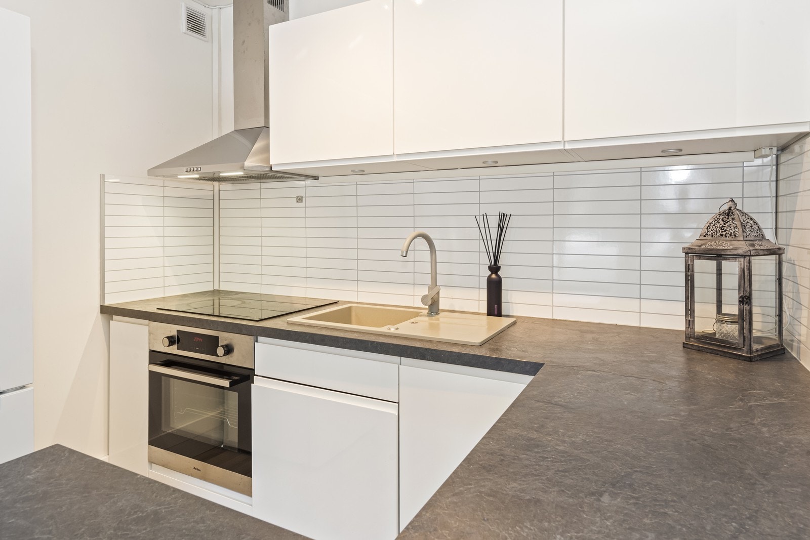 Kjøkkeninnredningen har hvite, glatte fronter, laminatbenkeplate og integrert stekeovn og platetopp. Galleribilde