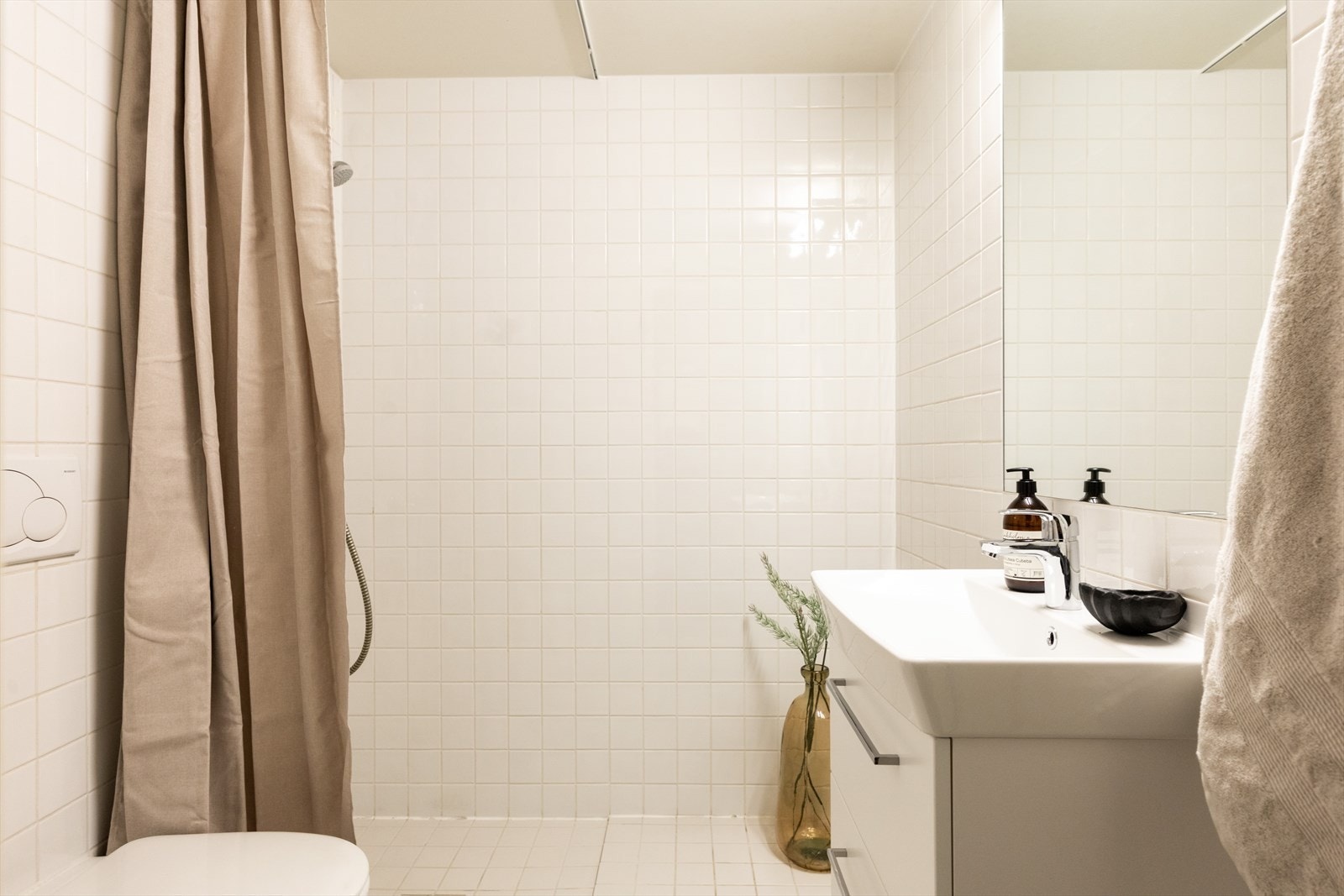 Flislagt og romslig bad fra byggeår, innredet med en nedfelt servant, overhengende speil og belysning. Dusjen er plassert i hjørnet og har håndholdt dusjarmatur samt dusjvegger. Galleribilde