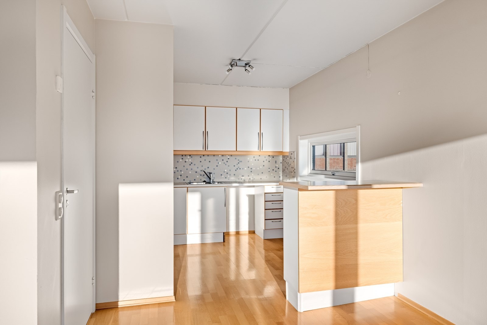Kjøkkeninnredning fra byggeår med glatte, folierte fronter, laminat benkeplate og fliser over benkeplaten. Galleribilde