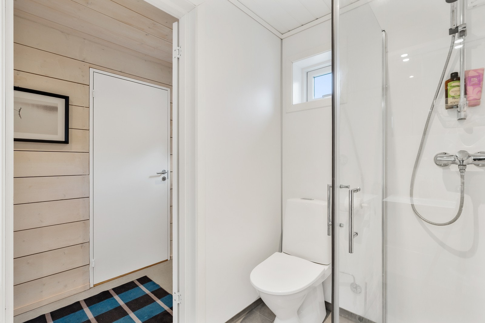 Rommet er innredet med baderomsinnredning med nedfelt servant, toalett og dusjhjørne med glassvegger. Det er opplegg for vaskemaskin. Galleribilde