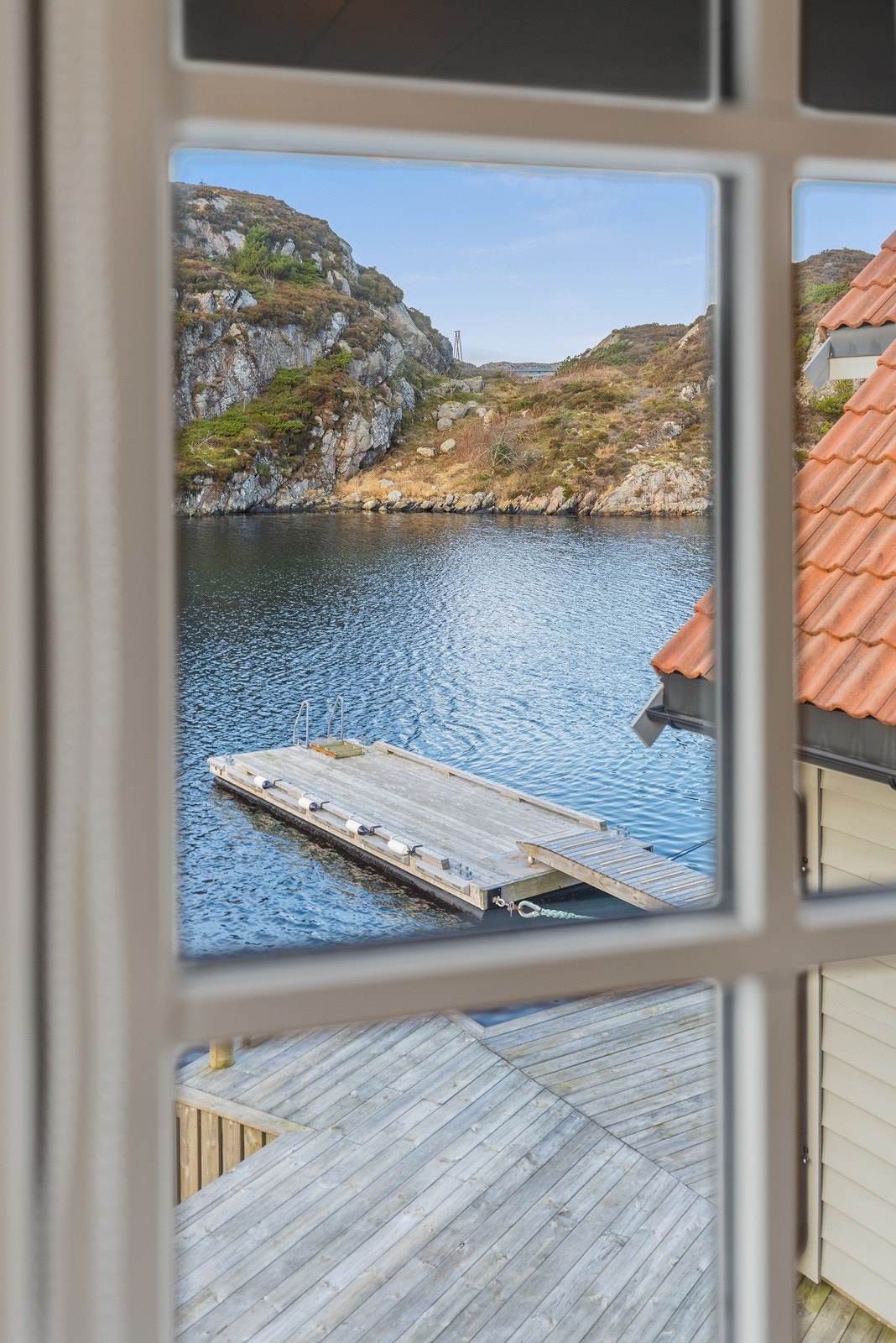 Utsikt fra vindu mot flytebrygge og omkringliggende natur. Galleribilde