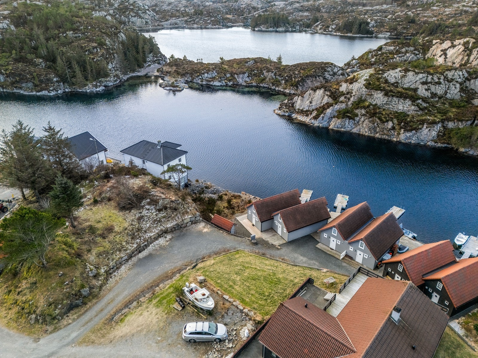 Oversiktsbilde av naustene og omkringliggende natur gir inntrykk av ro og privatliv. Galleribilde