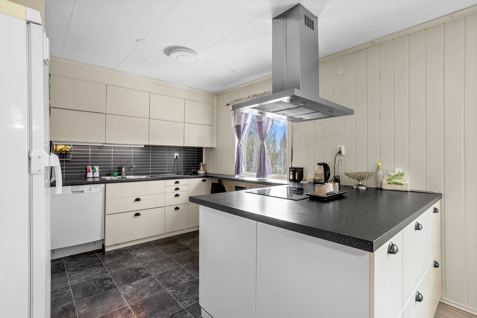 Kjøkken fra 2022 med slett innredning, laminat benkeplate og integrert platetopp og stekeovn. Galleribilde