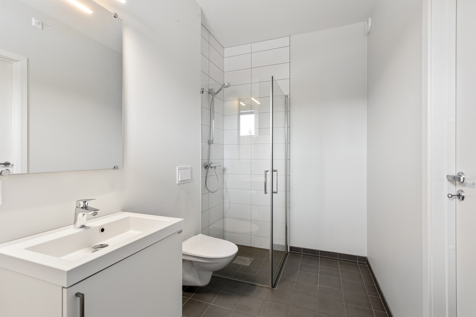 Stilren baderomsinnredning med servant, speil med belysning og stikkontakt. Galleribilde