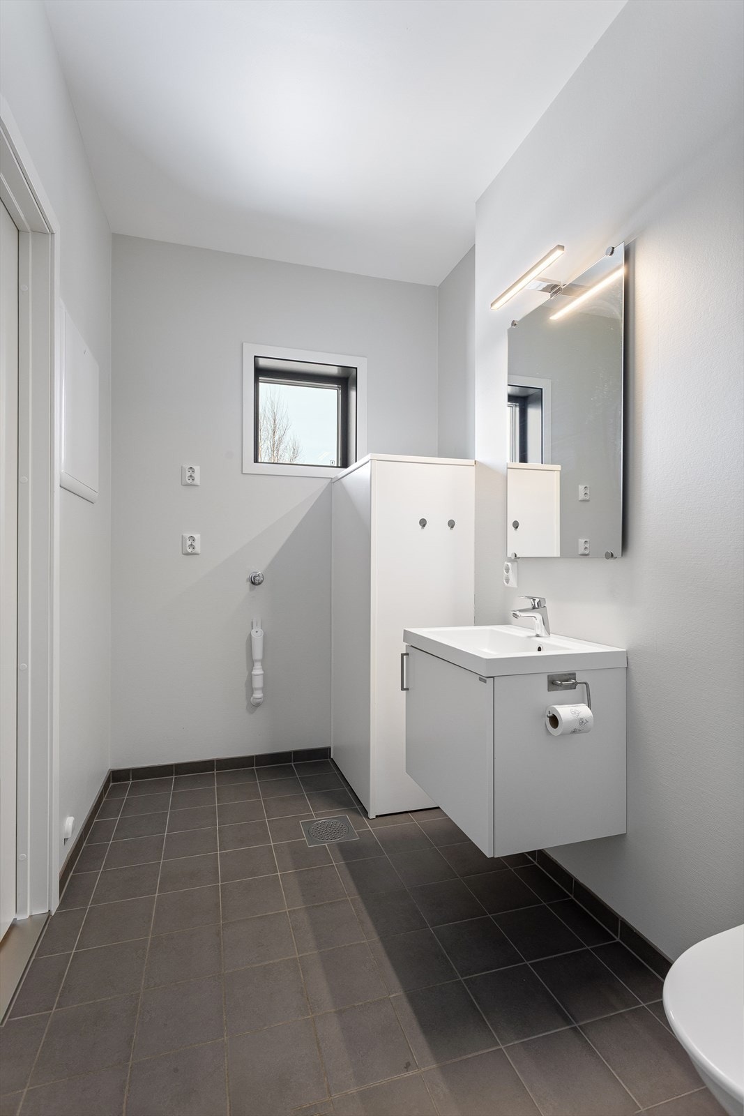 Badet har flislagt gulv med behagelig gulvvarme og praktisk opplegg for vaskemaskin. Galleribilde