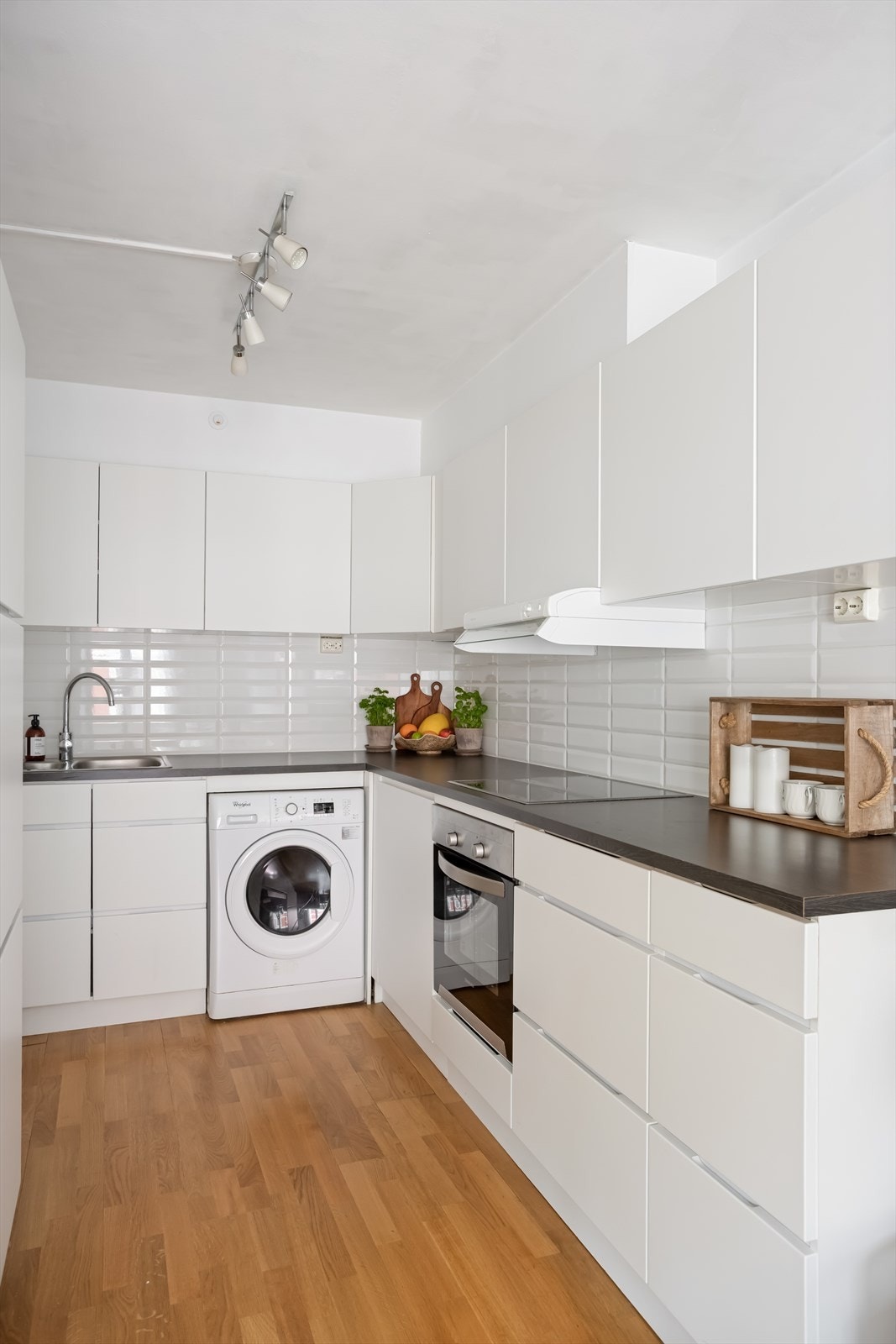 Kjøkkenet består av innredning med glatte, folierte fronter, laminat benkeplate med nedfelt kum i rustfritt stål og fliser på vegg over benk samt ventilator som er tilsluttet kanal. Galleribilde