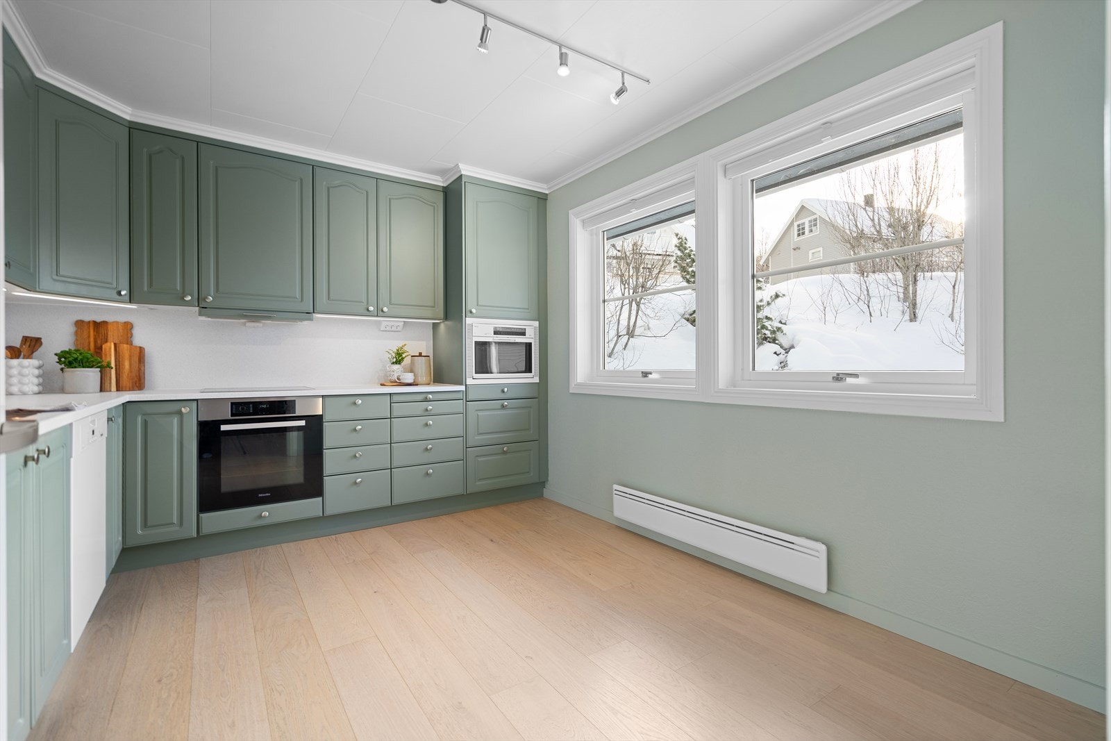 Kjøkken i delikate farger med rikelig med oppbevaringsplass og gode arbeidsflater. Malte, profilerte fronter gir kjøkkenet et stilrent og tidløst uttrykk. Galleribilde