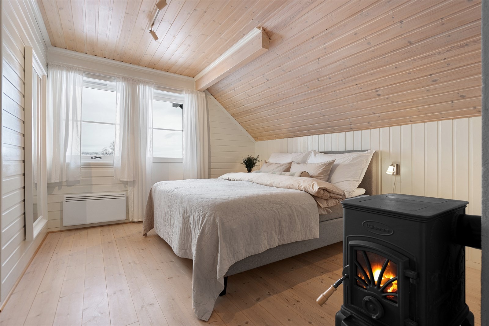 Romslig soverom med vedfyring som skaper lun atmosfære Galleribilde