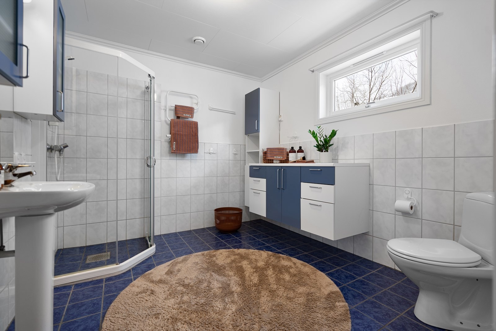 Flislagt bad i 2. etasje med elektrisk varme i gulv, dusjhjørne, toalett, servant med speil og rikelig oppbevaring i benkeskap. Galleribilde