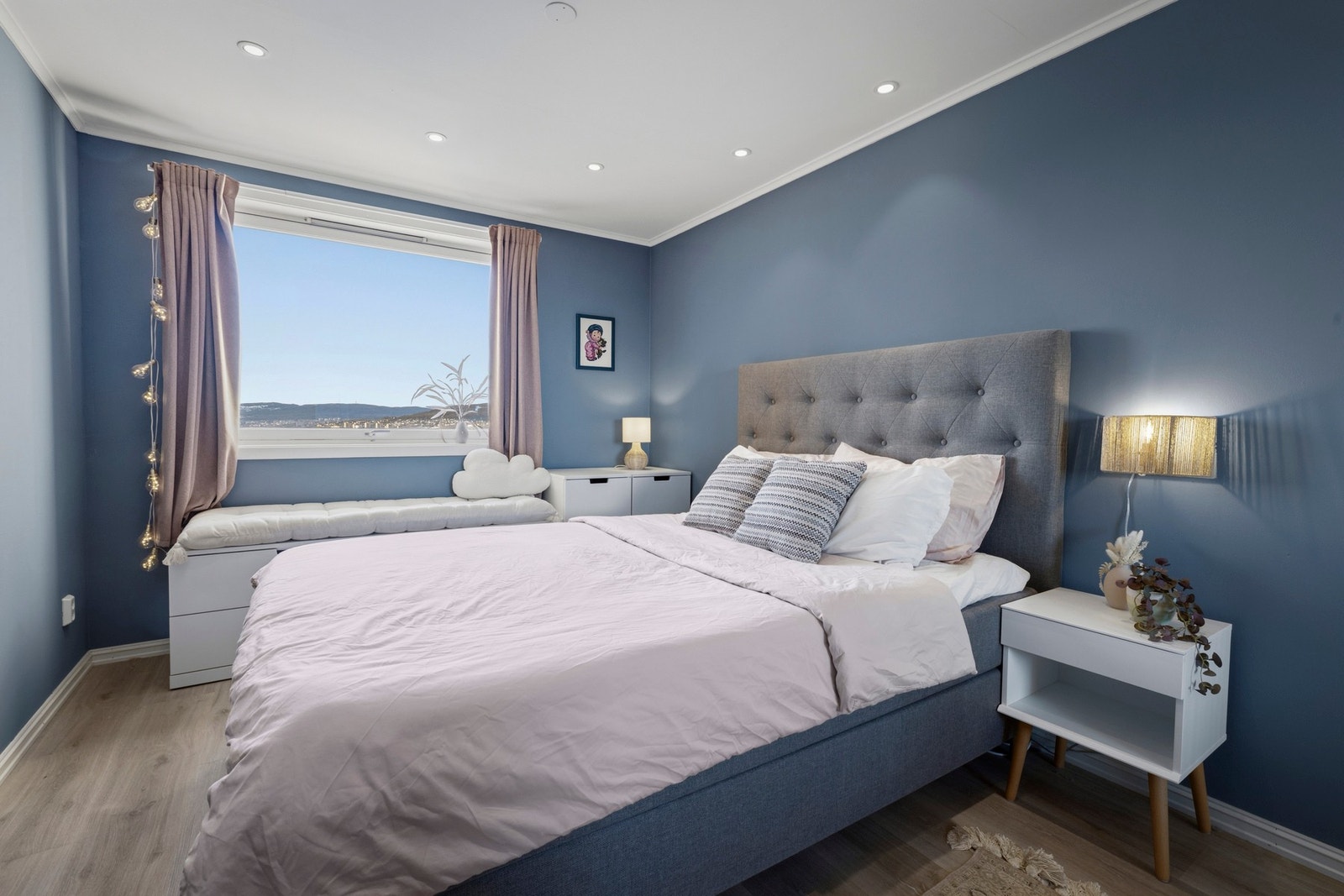 Leiligheten har et luftig og romslig soverom med vinyl på gulvet og vegger i en moderne blåfarge Galleribilde