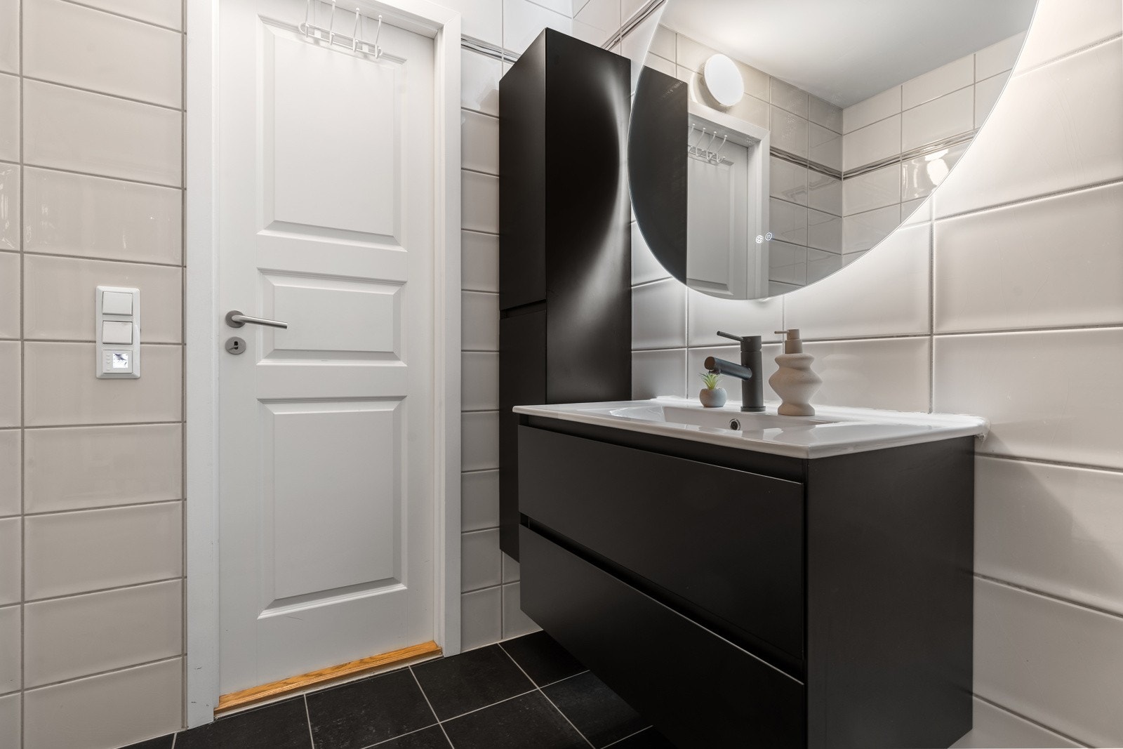 Badet har dusjkabinett, nedfelt servant, opplegg for vask og trommel samt speil med lys bak.