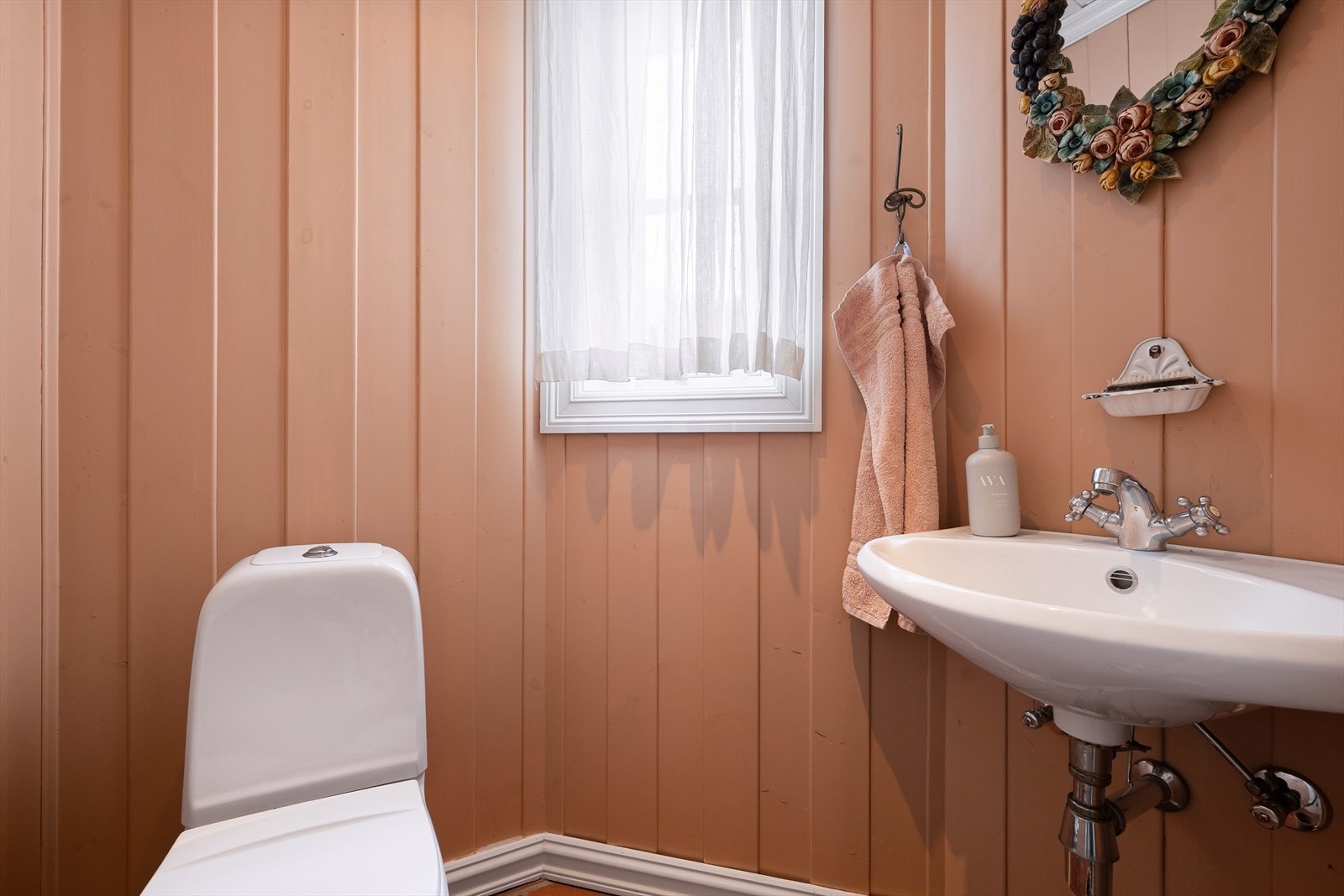 Praktisk WC med flislagt gulv, stående trepanel på vegger, gulvmontert toalett og servant Galleribilde