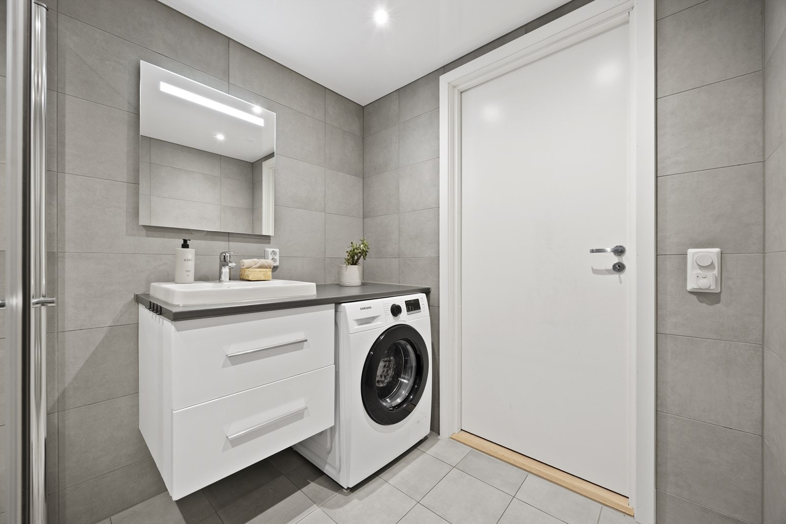 Badet har opplegg for vaskemaskin og innredning med glatte fronter. Galleribilde