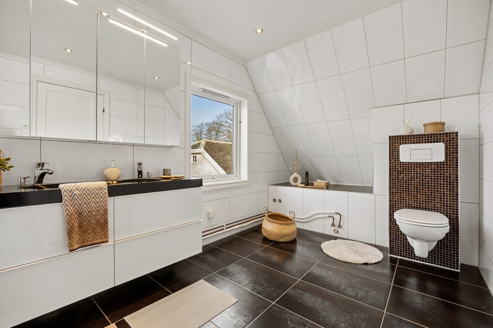 Rommet er innredet med en servantinnredning med nedfelte servanter, dusjkabinett, veggmontert toalett og opplegg for vaskemaskin. Elektrisk styrt vifte. Galleribilde