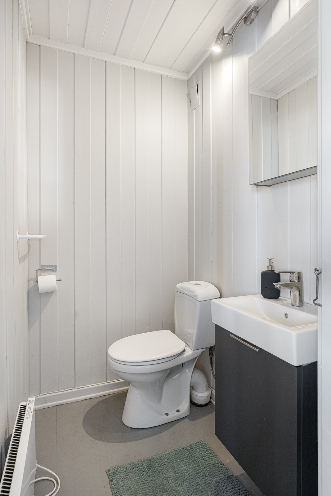 I hendig tilknytning til entreen i første etasje er det et separat wc-rom med lysmalt panel på veggene og gråmalt, originalt heltregulv. Servantskap, vask og armatur er fra 2025. Galleribilde