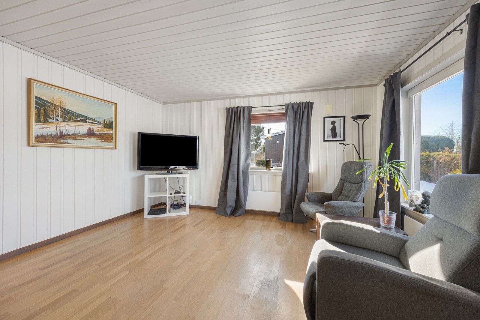 I stuen er det hvitmalt panel på veggene og lys parkett på gulvet. Galleribilde