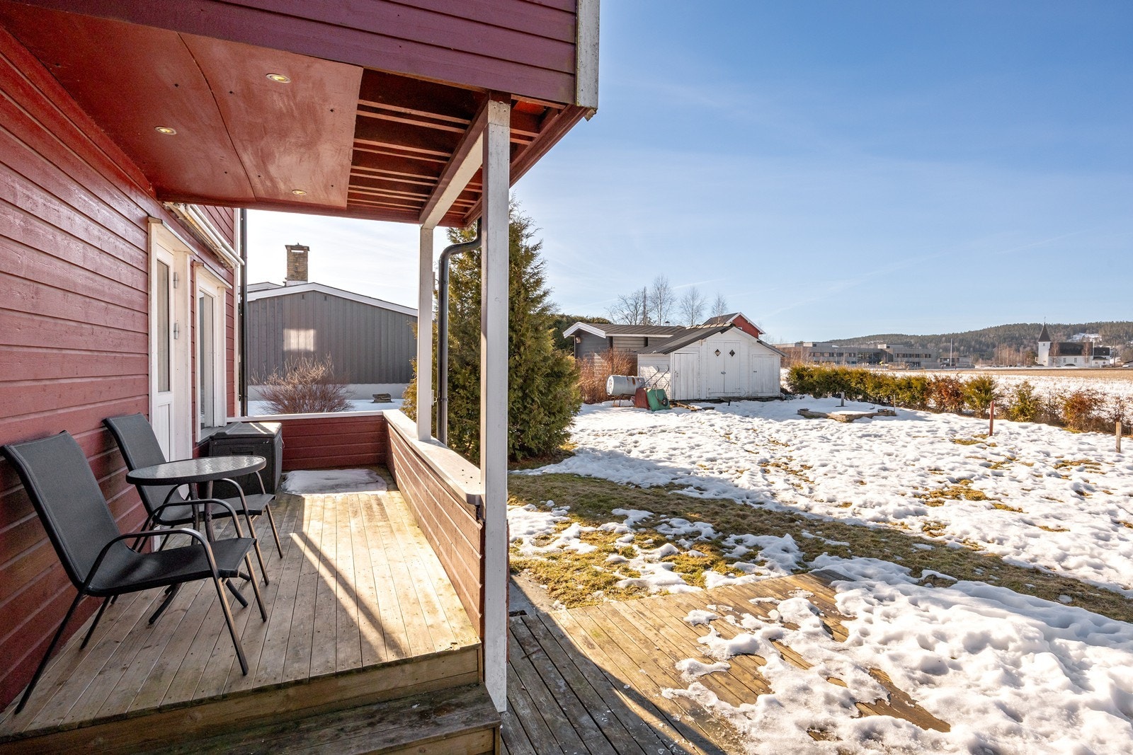 Terrassen har dekke og rekkverk i tre, og det er montert en bred markise på husveggen. Galleribilde