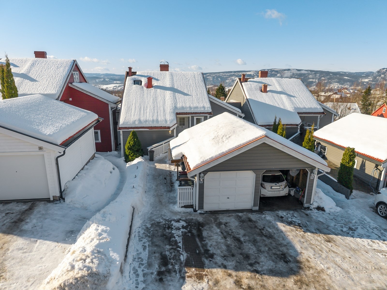 Steinbelagt gårdsplass med biloppstillingsplass i halvpart av dobbelgarasje, samt foran denne. Galleribilde