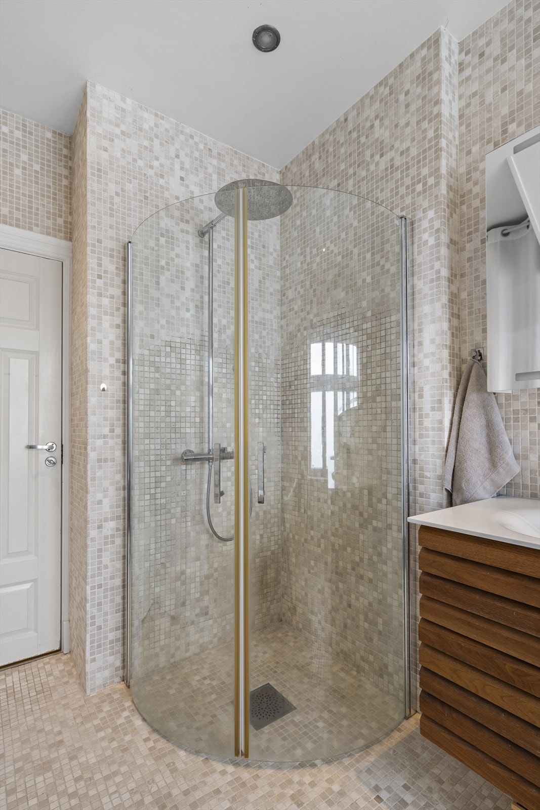 Badet er innredet med vegghengt toalett med innebygget sisterne, to servanter, badekar med dusjløsning, dusj med innfellbare dører i herdet glass. Galleribilde