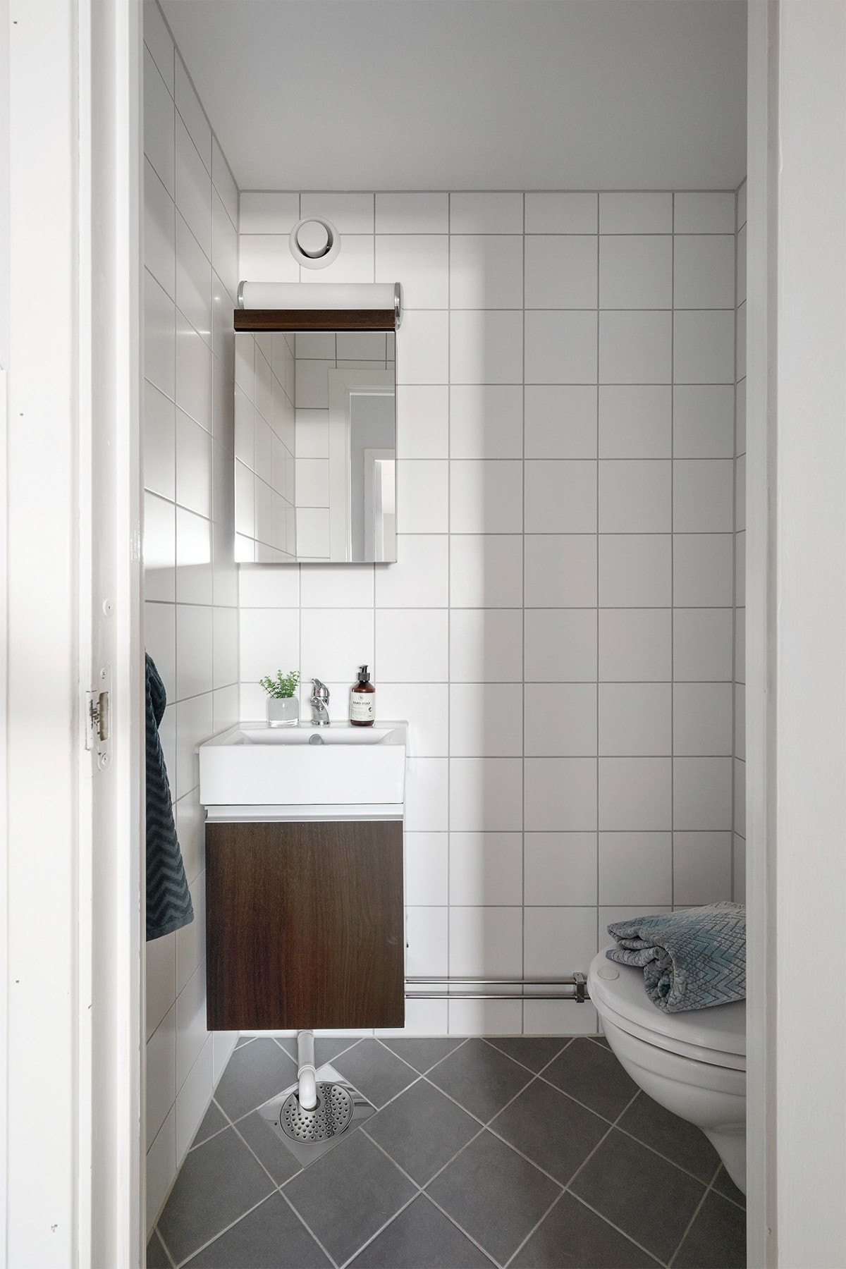 Separat flislagt toalettrom med servant med innredning og vegghengt toalett Galleribilde