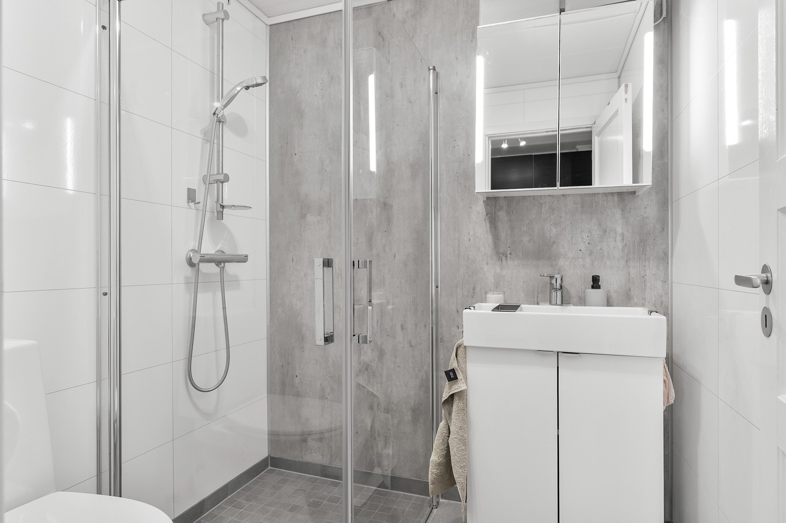 Badet er romslig og innredet med dusjhjørne med glassvegger, baderomsinnredning med servant og toalett. Galleribilde