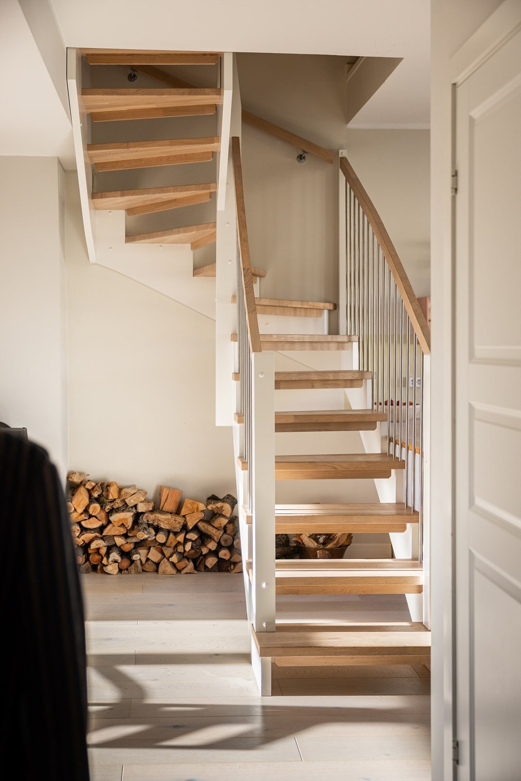 Den hvitmalte tretrappen med trinn i hvitpigmentert eik leder elegant opp til loftsetasjen. Galleribilde