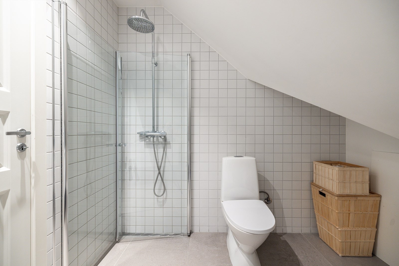 Dusjhjørne med svingbare glassdører i herdet glass og et frittstående toalett. Galleribilde