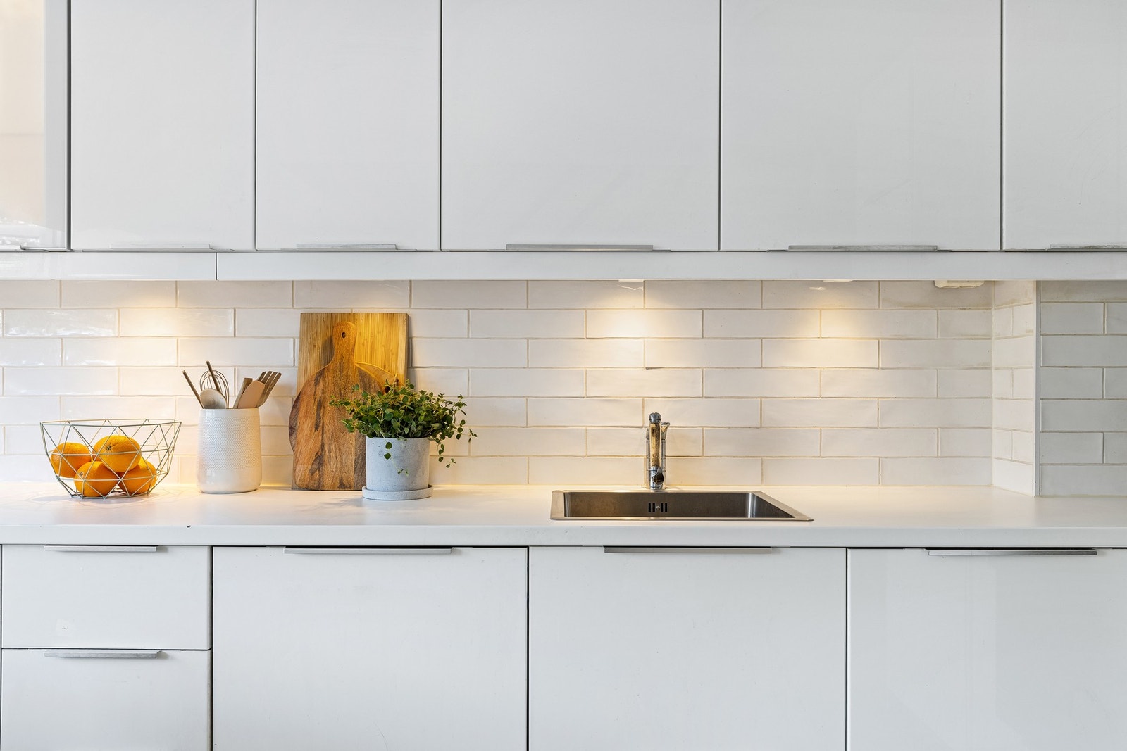 Kjøkkenet har benkeplater i laminat og nedfelt kum av stål. Fliser er satt opp over benkeplate Galleribilde