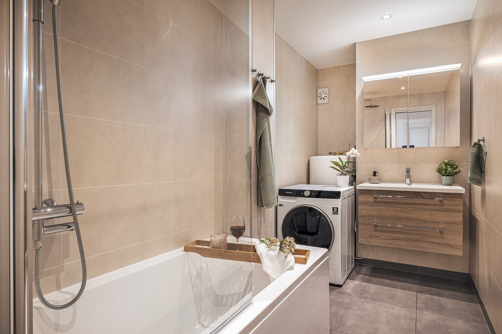 Pent bad med fliser på gulv med varmekabler. Våtromsplater på vegger og spotlights i tak. Galleribilde