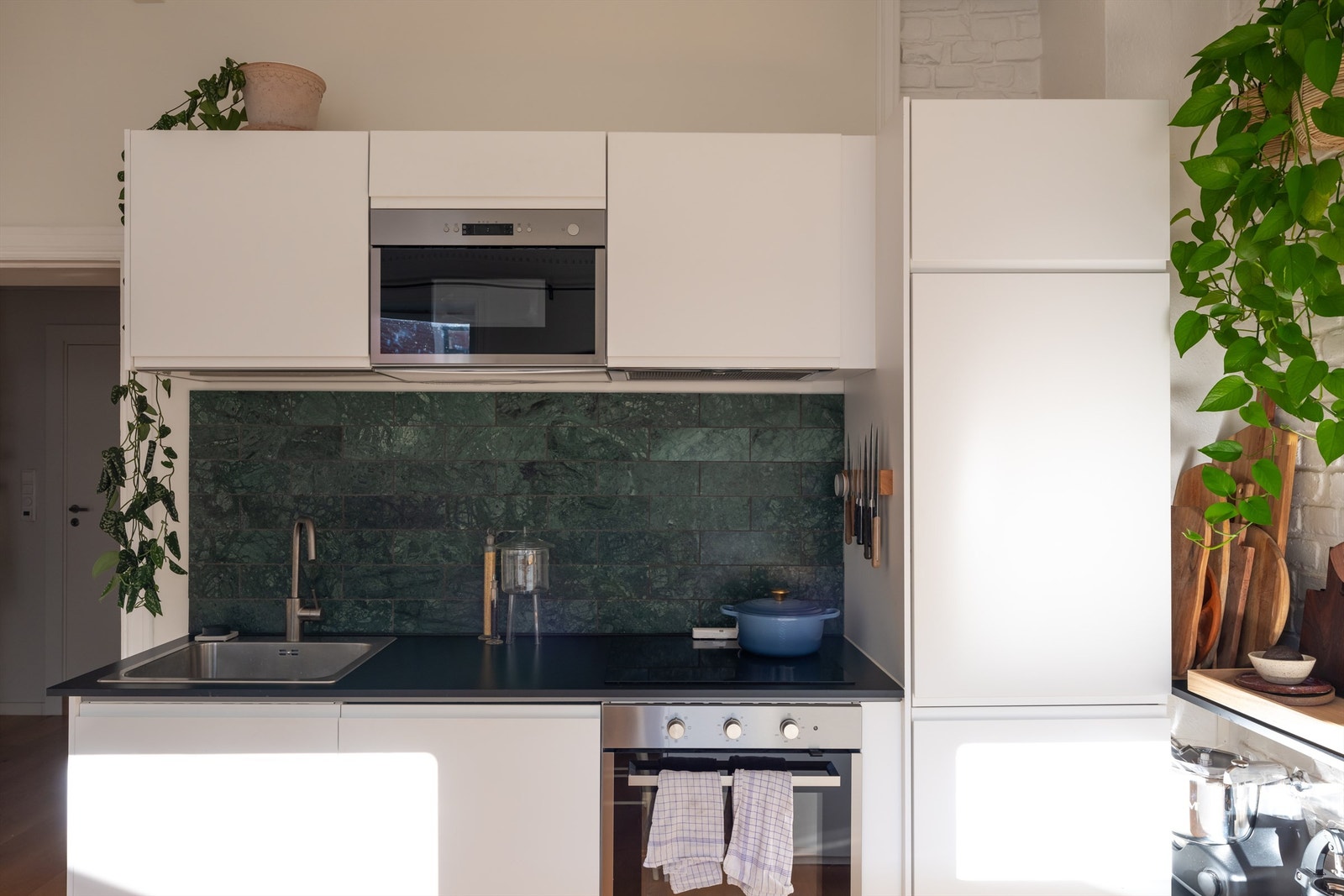 Flisene mellom kjøkkenbenken og overskapene bidrar til et varmt og tidløst uttrykk. Galleribilde