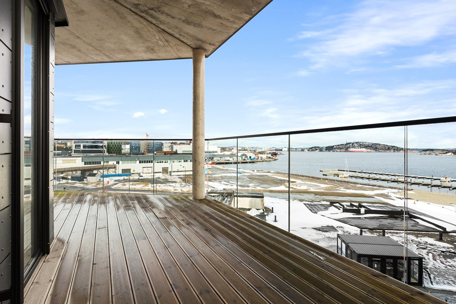 Balkong tilhørende aktuell leilighet er på hele 16 kvm. Den er overbygget og har terrassebord av tre. Legg merke til det flotte glassrekkverket. Galleribilde