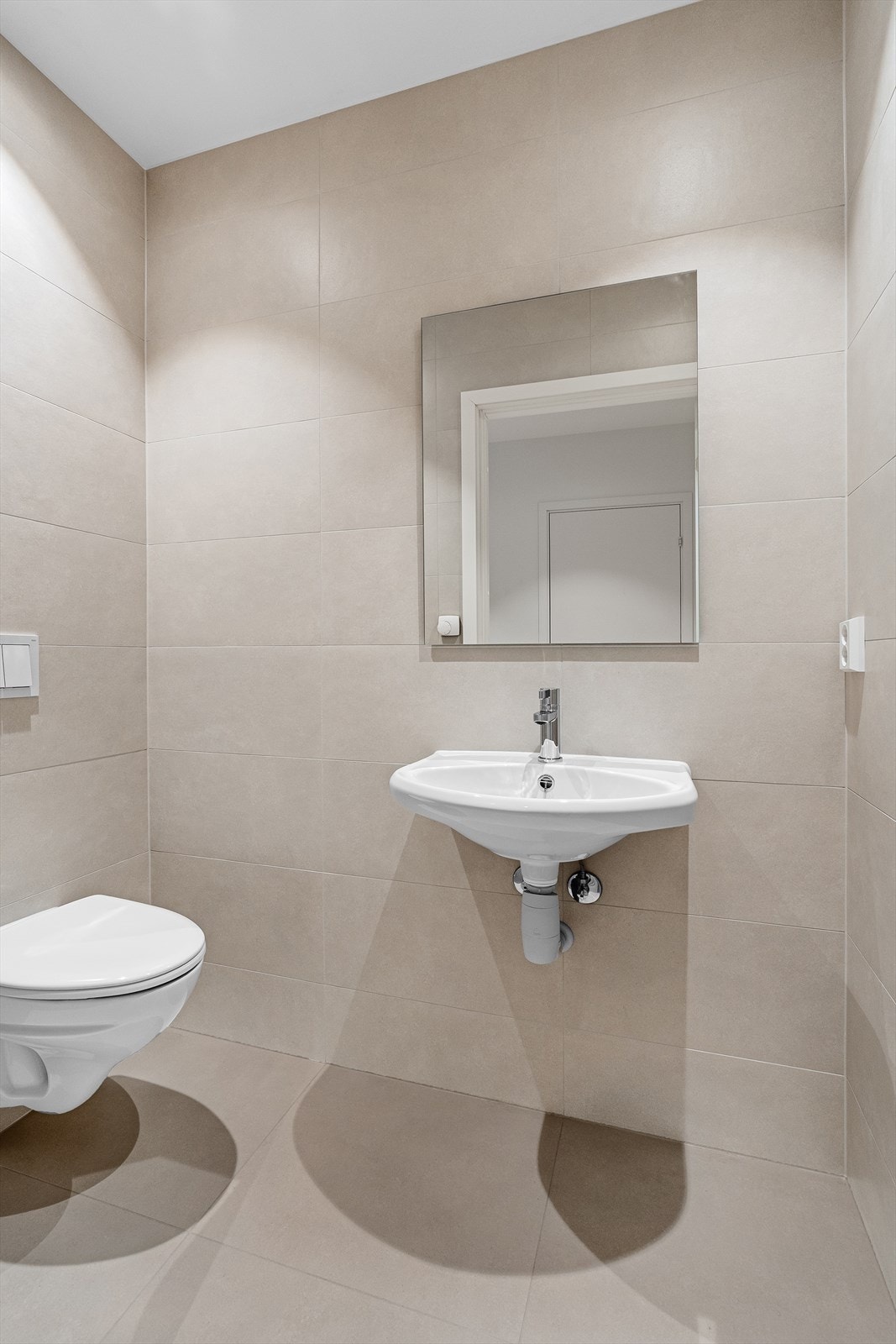 Toalettrommet er helfliset med tidsriktige fliser. Det inneholder et vegghengt toalett, samt vask med speil over. Galleribilde